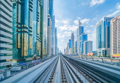 Railroad tracks amidst buildings in city against sky