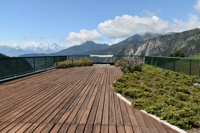 Footpath leading towards mountains against sky