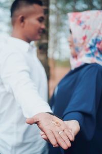 Side view of couple hands holding wedding rings