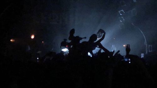 Silhouette people enjoying music concert at night