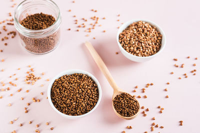 Raw buckwheat tea in a bowl and wooden spoon and buckwheat on the table