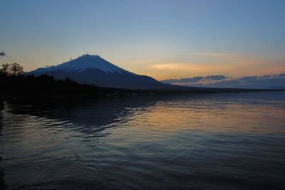 Scenic view of sea and mountains against sky during sunset