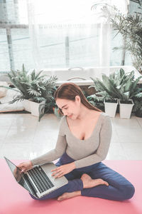 Young woman using phone while sitting on floor