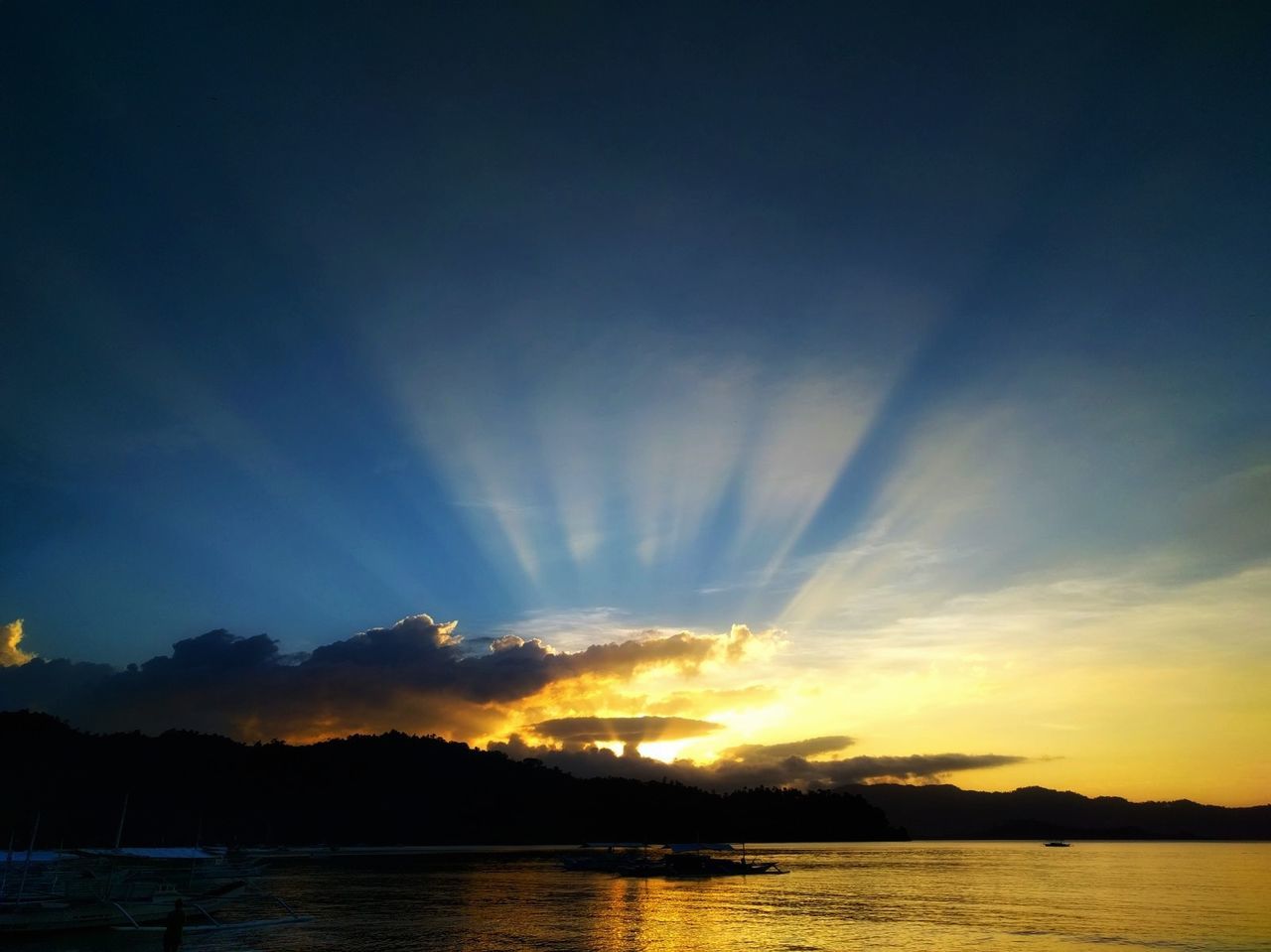 sunset, scenics, beauty in nature, tranquility, sky, nature, tranquil scene, water, silhouette, idyllic, majestic, sea, cloud - sky, reflection, outdoors, sun, waterfront, no people, sunlight, mountain, horizon over water, day