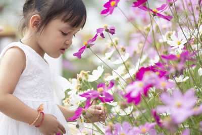 Side view of young woman standing amidst flowers