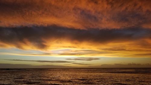 Scenic view of sea against dramatic sky during sunset