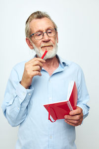 Portrait of young man holding dentures against white background