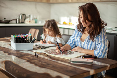 Mother and daughter drawing at home