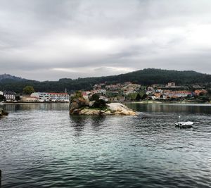 Scenic view of river by buildings against sky