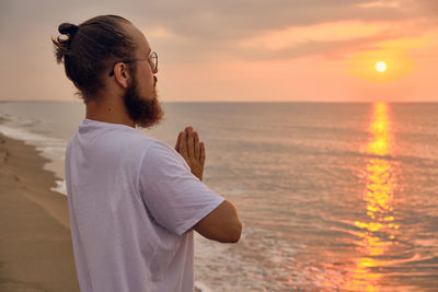 Man doing surya namaskar or salute to the sun or sun salutation. man practices yoga at sea beach