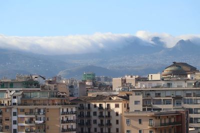 Buildings in city against cloudy sky