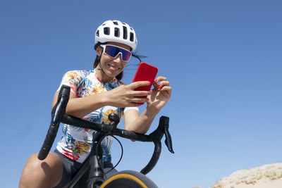 Happy cyclist using smart phone sitting on bicycle