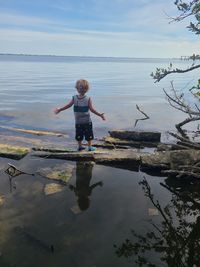 Rear view of boy on water against sky