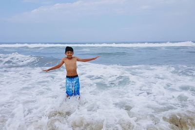 Boy standing on beach against sky