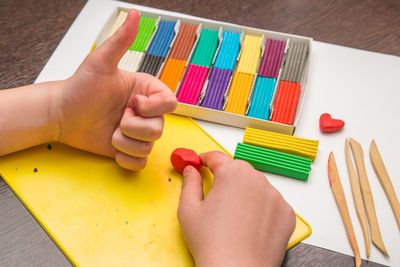 High angle view of baby hand holding paper on table