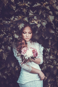 Beautiful bride standing amidst plants
