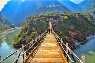 Footbridge amidst trees against sky