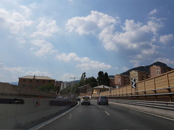 Road amidst buildings in city against sky