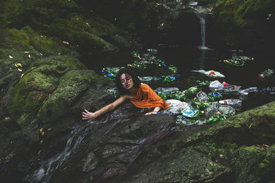 High angle view of woman amidst plastic bottles in water