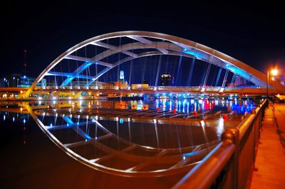 Illuminated bridge over river in city at night