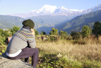 Rear view of woman standing on field against mountains