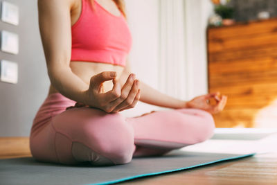 A young woman sits in the lotus position and meditates at home or in a yoga class and meditates. 