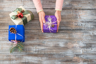 High angle view of woman holding christmas gift on wooden table