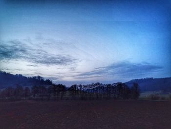 Trees on field against sky at dusk