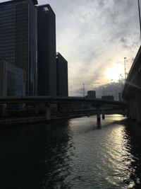 River in city against sky during sunset