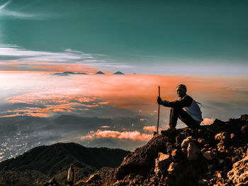 Man standing on rock against sky