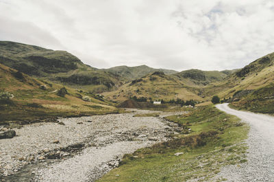 Scenic view of road by mountains against sky