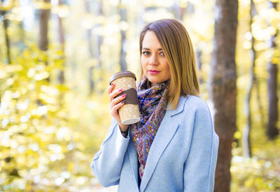 Portrait of smiling young woman standing against glass