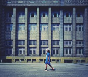 Woman walking on street against building in city