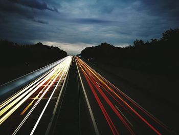 Light trails on road against sky at night