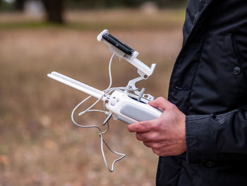 Midsection of man using drone remote control on land