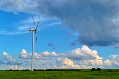 Low angle view of wind turbines on field against sky