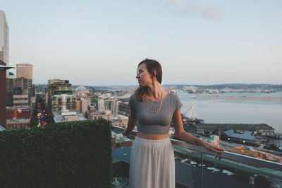 Woman standing by railing against sky