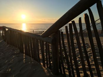 Close-up of railing on beach against sky during sunset