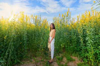 Portrait of young woman standing against flowering plants