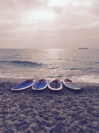 Surfboards on shore at beach against sky