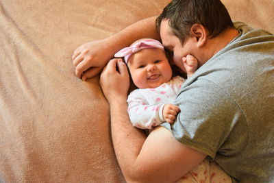 High angle view of smiling baby with father on bed