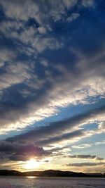 Scenic view of sea against cloudy sky at sunset