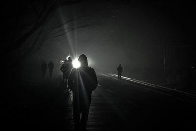Silhouette people walking on road at night
