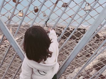 Rear view of woman standing by chainlink fence