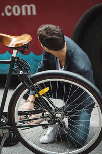 Businessman repairing bicycle on street
