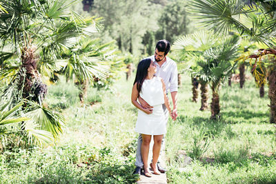 Full length of young woman standing on palm tree