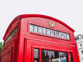 Low angle view of red telephone booth against sky