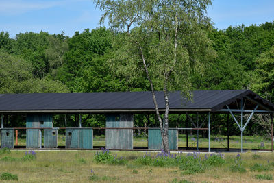 Built structure on field by trees against sky