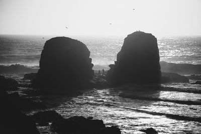 Scenic view of rocks on sea against clear sky