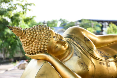 Close-up of buddha statue against sky